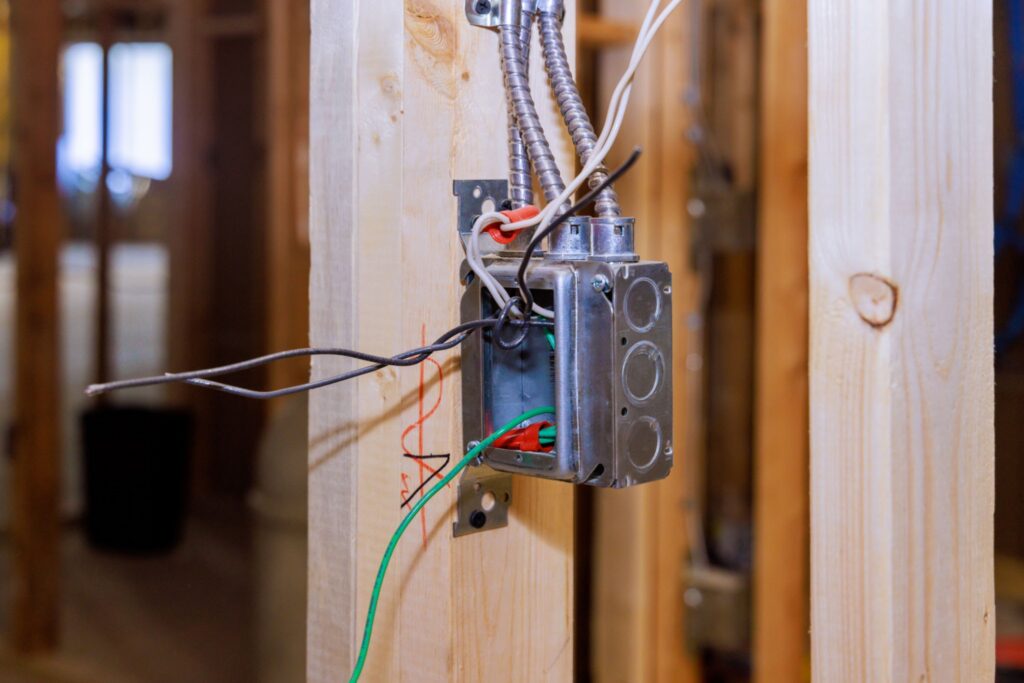 Electrical junction box with exposed wiring mounted on a wood stud wall during home construction